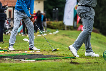 Golfer legs at golf tournament practice swing with golf club.