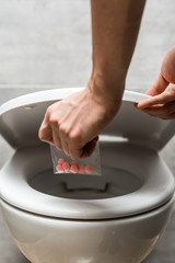 cropped view of man throwing away lsd in toilet bowl