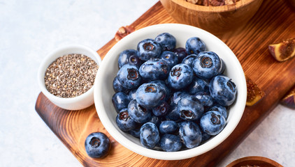 selected blueberries in a ceramic bowl on a wooden cutting board, top view