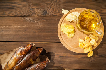 Beer glass with beer and hot smoked fish close-up. Beer mug with beer and fish on a dark background and copy space.