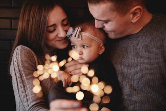portrait of happy family, mom, dad and baby girl with sparklers in front. family in anticipation of Christmas. selective photo.