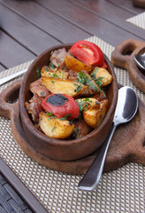 Roasted meat with potatoes, ojaxuri, hot in Georgian on a wooden table. Georgian cuisine