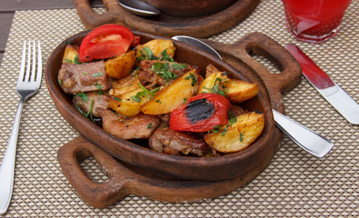 Roasted meat with potatoes, ojaxuri, hot in Georgian on a wooden table. Georgian cuisine