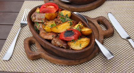 Roasted meat with potatoes, ojaxuri, hot in Georgian on a wooden table. Georgian cuisine