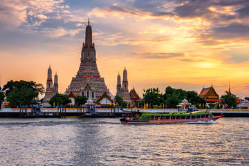 Naklejka premium Grand Pagoda of Wat Arun Temple of Dawn with Tourist Sightseeing Boat in Chao Phraya River at Sunset, Bangkok
