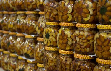 Glass jars filled with honey, nuts and fruit on the store counter