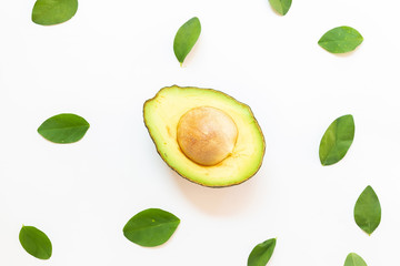 Avocado with green leaves on a white background. Green healthy fruit that is split in half and has a large seed inside.