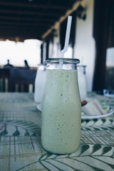 A glass of organic avocado shake on the table. Selective focus. Portrait orientation.