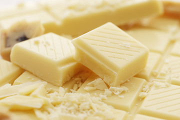 A lot of different White chocolate pieces and a bar closeup as a background. Top view. Place for text.