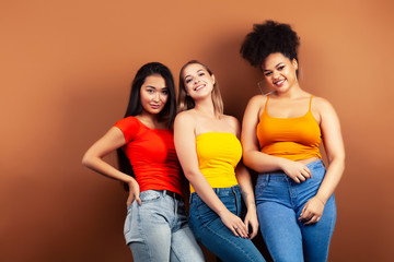 young pretty multiracial girls posing cheerful on brown background, lifestyle people concept
