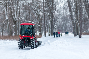 tractor cleans the road from snow in a winter park