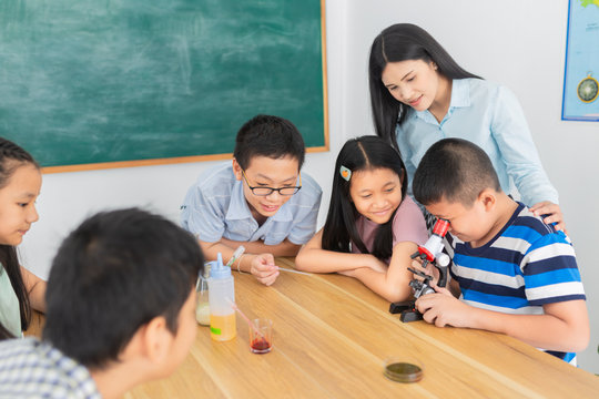 asian student group learning chemical solvent in science education class, asian boy looking something in glass tray with microscope , they feeling fun and wonderful
