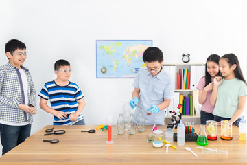 Fototapeta premium asian student group learning experimentation and chemical solvent in science education class, asian boy wear glove and holding glass bottle, they feeling happy and wonderful