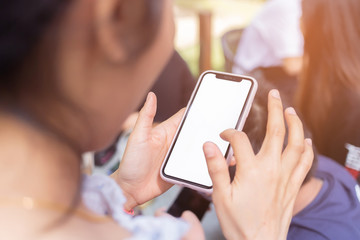 Asian woman is using a smartphone in a coffee shop with white sceen and clipping path. Mobile phones with white screens on the hands of women in convenience stores.