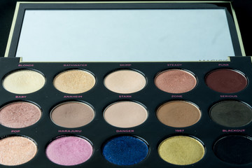 Make-up colorful eyeshadow palettes isolated on black background. View from above. 