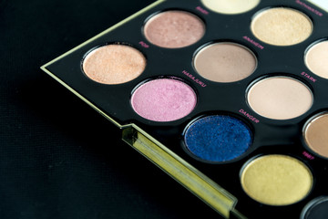 Make-up colorful eyeshadow palettes isolated on black background. View from above. 