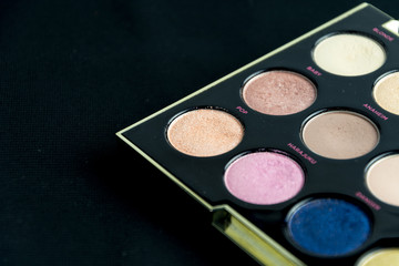 Make-up colorful eyeshadow palettes isolated on black background. View from above. 