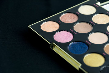 Make-up colorful eyeshadow palettes isolated on black background. View from above. 