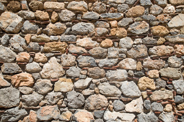 Colorful ancient stone wall with pieces of ceramics  closeup