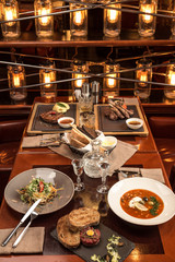 Gourmet meals assorted set on wooden table Buffet at restaurant with light bulbs