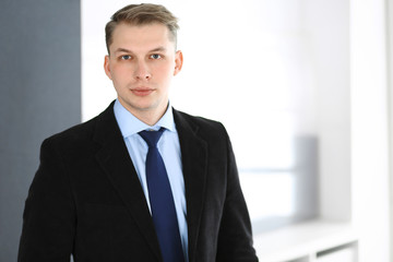 Headshot of businessman standing straight in office. Success and business workplace concept
