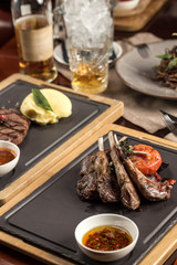 Lamb rib chops grilled with sauce on stone board on wooden table at restaurant
