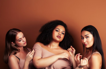 young pretty asian, caucasian, afro woman posing cheerful together on brown background, lifestyle diverse nationality people concept