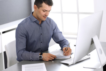 Businessman working with computer in modern office. Headshot of male entrepreneur or company...