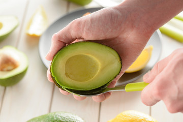 Man preparing avocado, scooping its flesh out with a spoon