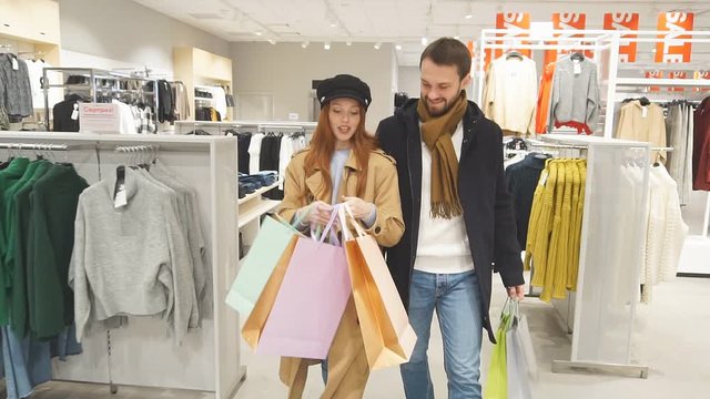 Young caucasian couple happily shopping in clothes store together, spend free time in shop. shopaholic concept