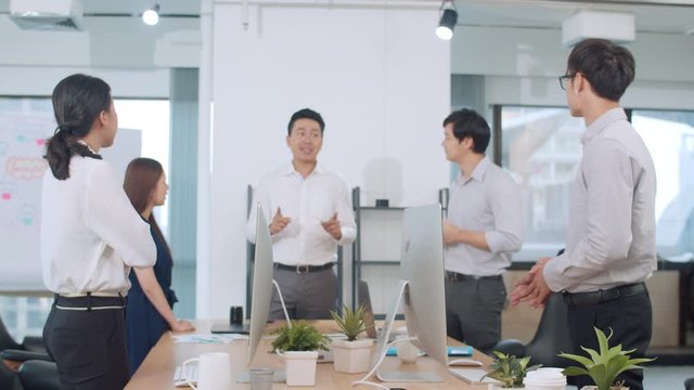 Millennial group of young businesspeople Asia businessman and businesswoman celebrate giving five after dealing feeling happy and signing contract or agreement at meeting room in small modern office.