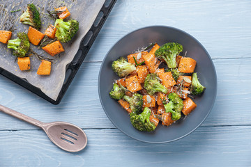 Baked broccoli and pumpkin in a plate. next to a tray with baked broccoli and pumpkin in the oven....