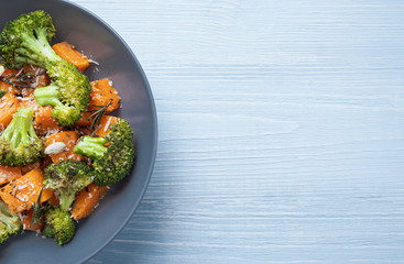 Salad in a round plate of baked broccoli and pumpkin. sprinkled with parmesan.