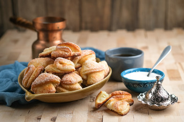 Homemade cookies with cottage cheese in a ceramic bowl and copper coffee cezve on a wooden background..