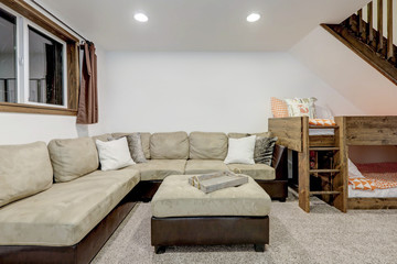 Living room with build in bunk bed under staircase for extra sleeping spaces and large beige sofa.