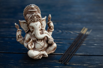 Hindu god Ganesh on black background. Statue on wooden table