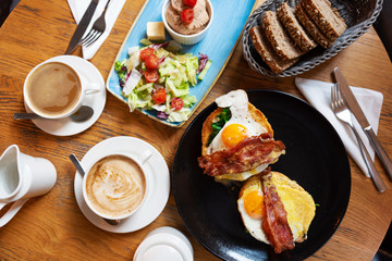 English breakfast in the morning in restaurant on a wooden table. Fried egg, bacon, vegetable salad with bread on a plate as a helathy meal. Coffee cup. Lunch time. Flat lay and top view.