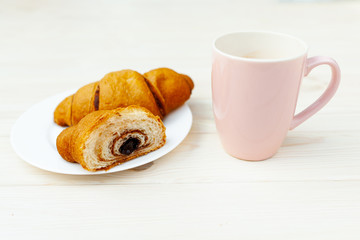 Fresh Croissant with chocolate on the white wooden background