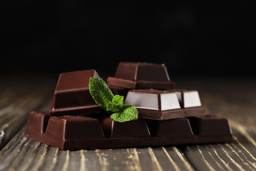 Broken black chocolate pieces   on brown table. Copy space.