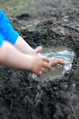 child arms playing with mud, creating a pond with happiness