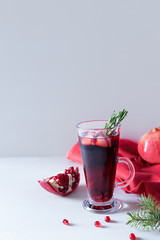 Pomegranate Christmas cocktail with champagne, soda and rosemary on a white table. Xmas drink.