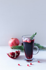 Pomegranate Christmas cocktail with champagne, soda and rosemary on a white table. Xmas drink.