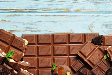 Different pieces of milk chocolate on a blue wooden background. Top view. Place for text.