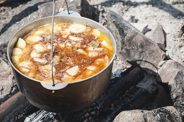 Spicy tourist soup with vegetables boils in a cauldron