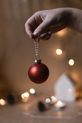 A hand holds a red christmas bauble in front of a scandinavian christmas decor