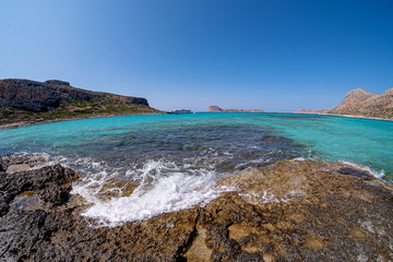 spray from the crashing waves on the rocks against the blue sky fish eye