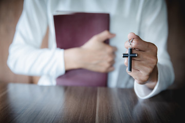 A young woman hugged the Bible and held a cross. Considered as a sacred blessing of God Spirituality and worship and praise of Christians And religious beliefs. Asking for a blessing.