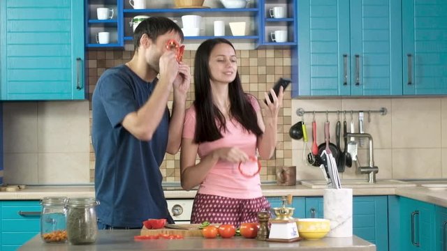 man and woman are having fun cooking Breakfast of vegetables and dancing. fool around have fun and put to face chopped paprika. Selfies in the kitchen. funny photos in the kitchen for social networks