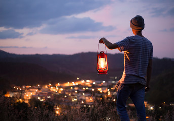 young man holding an old lantern  to illuminate