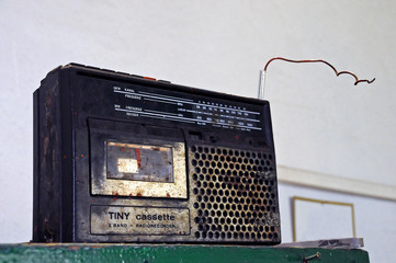 A dirty old radio cassette player on a shelf.